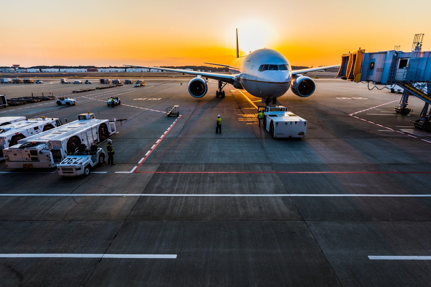 Wide-body aircraft at the gate at sunset with ground crew