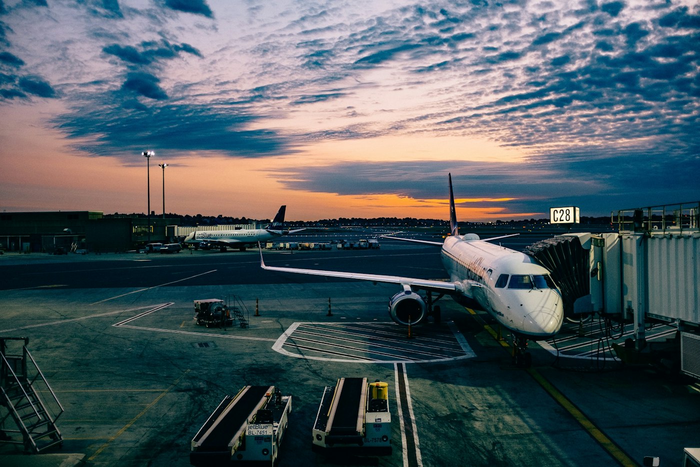 Airliner at the jet bridge on an apron at sunset with ground support equipment