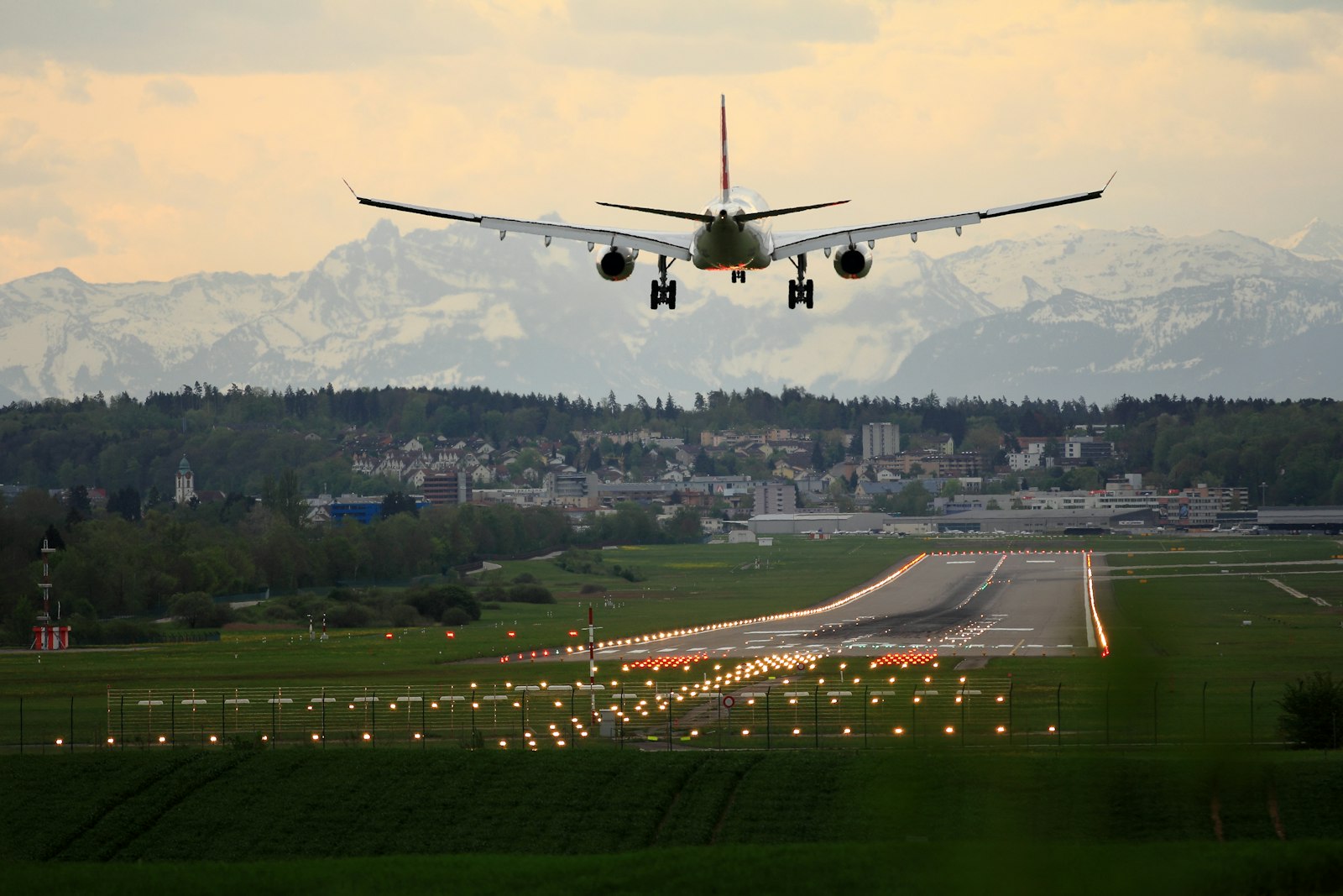 Airliner on final approach to a lit runway with mountains behind